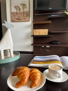 two croissants and a cup of coffee on a table at CR MARIPOSA RENTALS Cozy Retreat with Pool,Tennis,Gym,Free WiFi in Santa Ana