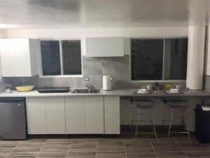 a kitchen with white cabinets and bar stools at El Rincon Amarillo. Zona Dorada. in Tijuana