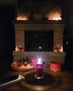 a candle on a table with a basket of apples and a fireplace at Kukułka Mazury in Ruciane-Nida