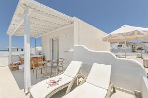a balcony with white chairs and an umbrella at Elite Suites Naxos in Naxos Chora