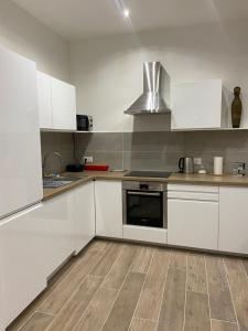 a kitchen with white cabinets and a stove top oven at Appartement chic plage des Catalans in Marseille
