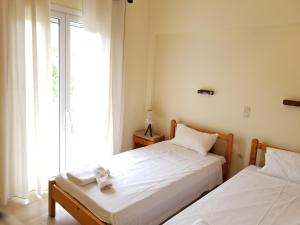 two beds in a room with a window at Corfu Escape Five ( Leonidas Studios) in Agios Georgios Pagon