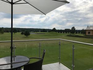 a balcony with a table and chairs and an umbrella at Apartament Golf & Lake in Kalinowo