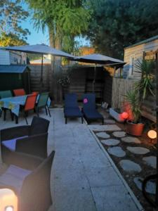 une terrasse avec des chaises, des tables et un parasol dans l'établissement Mobil home bungalow 6 personnes villeneuve loubet plage marina baie des anges, à Villeneuve-Loubet