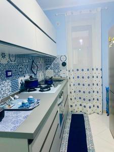 una cucina con piastrelle bianche e blu sul muro di Casa Limoni al mare tra Catania Etna e Taormina ad Acireale