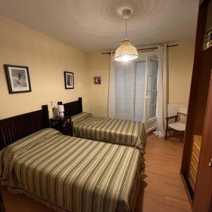 Habitación de hotel con 2 camas y lámpara de araña. en Casa La Hayuela Molleda en Ayuela