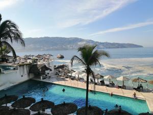 a swimming pool next to a beach with umbrellas at Apartamento Torres gemelas in Acapulco