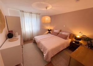 1 dormitorio con cama blanca y ventana en Ferienwohnung Ptit Monde, en Friedrichshafen