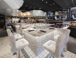 a restaurant with white chairs and a large counter at Hôtel Boutique Ophelia - Par Aneyro in Quebec City
