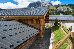 ein Gebäude mit einem Metalldach mit einem Berg im Hintergrund in der Unterkunft Chalet La Canopée in La Giettaz