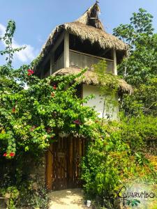 una pequeña casa con techo de paja y flores en Guarumbo en Bacalar