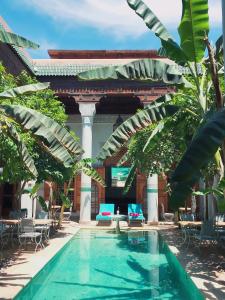 a pool in the courtyard of a building with chairs and trees at Riad Slitine & Spa in Marrakesh