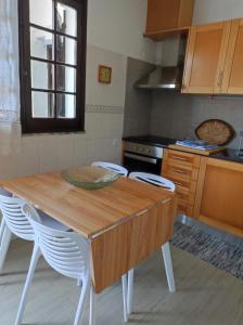 ナザレにあるComfort Beach houseのキッチン(木製テーブル、白い椅子付)