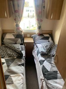 two beds in a small room with a window at Prestige Static Caravan on 5 Star Holiday Park in Cheswick