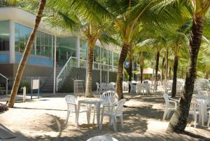 einen Tisch und Stühle unter Palmen vor einem Gebäude in der Unterkunft Angra Super Luxo in Mangaratiba