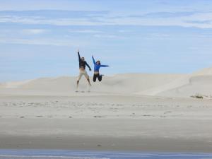 twee mensen springen in het zand in de woestijn bij Hotel Isabela in San Carlos