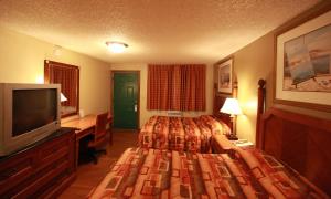 a hotel room with a bed, television and a desk at Executive Motel in Eugene