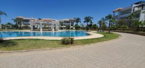 a swimming pool in a park next to a building at Asilah Marina Golf in Asilah