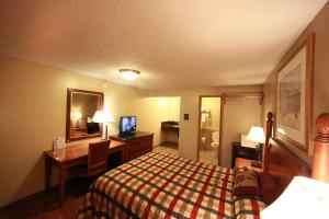Habitación de hotel con cama, escritorio y espejo. en Executive Motel, en Eugene