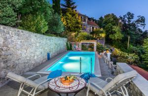 a swimming pool with a table and chairs next to a house at Villa Blanka in Žrnovnica