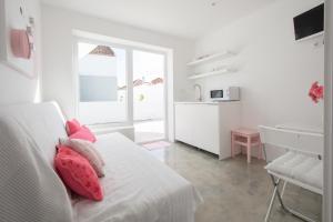 Habitación blanca con cama con almohadas rosas en CASASUPERTUBOS® Villa 9 & Apart 1-8, en Atouguia da Baleia