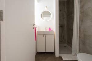 Baño blanco con lavabo y espejo en CASASUPERTUBOS® Villa 9 & Apart 1-8, en Atouguia da Baleia