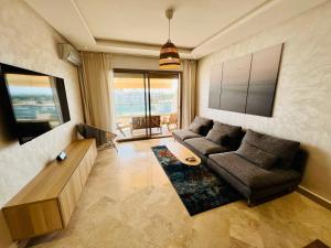 sala de estar con sofá y TV en OceanParc - Vue sur Mer et Parc 24H Sécurité, en Mohammedia