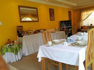 a dining room with white tables and chairs and a mirror at Alicia's B&B in Roodepoort
