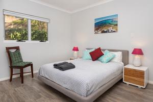 a bedroom with a bed and a chair and two windows at VILLA 17 CAPE VILLAS in Dunsborough