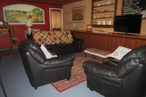 a living room with two leather chairs and a television at Bentwood Olive Grove Accommodation in Greenough