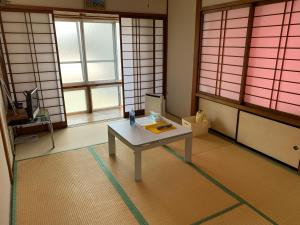 a room with a table in a room with windows at Buchoho No Yado Morioka in Morioka
