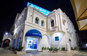 a large white building with a blue sign on it at Al Jumhour Hotel Apartments in Sur