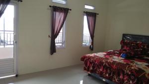 a bedroom with a bed and two windows at wijayanti's villa in Probolinggo