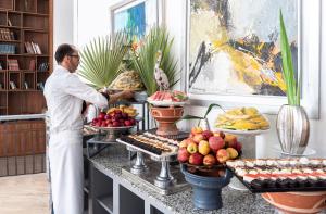 un hombre parado frente a un buffet con comida en Wazo Hotel, en Marrakech