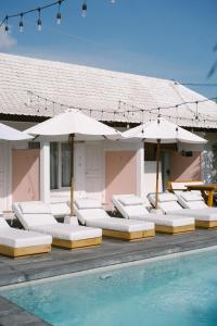 a group of lounge chairs and umbrellas next to a pool at Love Song Boutique Hotel in Canggu
