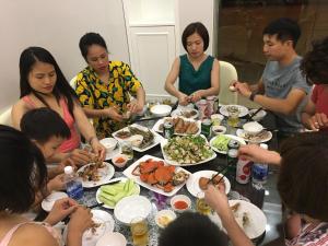 a group of people sitting around a table eating food at Moc Tra Hotel Tuan Chau Hạ Long in Ha Long