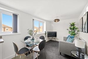 曼徹斯特的住宿－NEW 4 Sarah House by Truestays - 2 Bedroom Apartment - FREE Wifi & Parking，客厅配有桌椅和电视。