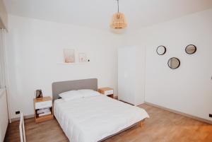 ein weißes Schlafzimmer mit einem weißen Bett und 2 Tischen in der Unterkunft "Envie Lyonnaise" Location - 10 personnes - Terrasse - WIFI Fibre optique in Lyon
