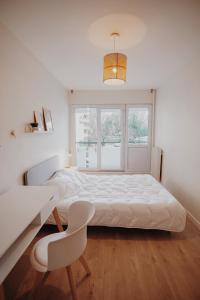 a white bedroom with a bed and a desk and a window at "Envie Lyonnaise" Location - 10 personnes - Terrasse - WIFI Fibre optique in Lyon