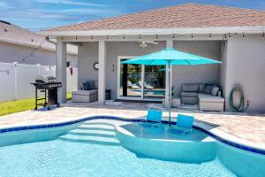 a swimming pool with two blue chairs and an umbrella at #11 Largo NW Luxurious Spacious House with a Beautiful Heated Pool in Largo