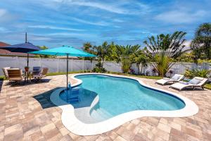 een zwembad met een parasol en een tafel en stoelen bij #11 Largo NW Luxurious Spacious House with a Beautiful Heated Pool in Largo