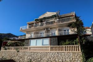 a building with a balcony on top of a stone wall at Apt and rooms Marlene - 50 m from sea in Milna