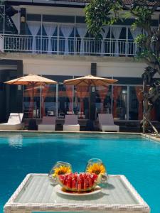 a tray with a bowl of fruit on a table next to a pool at Villa Agung Beach Inn in Lovina