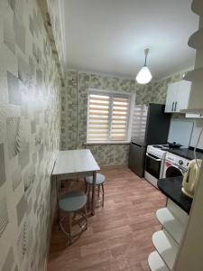 a small kitchen with a table and chairs in it at Апартаменты Балхаш in Balqash