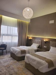 Habitación de hotel con 2 camas y lámpara de araña. en فلل السيف الخاصة en Abha