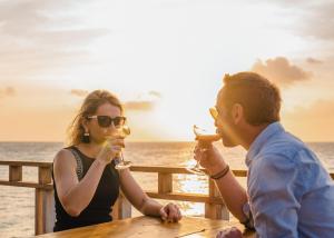a man and a woman sitting at a table with drinks at Furaveri Maldives in Raa Atoll