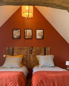 two beds in a room with an orange wall at Les Clématites, maison de campagne. in Boissy-lès-Perche