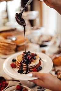 a person is drizzling syrup on a stack of pancakes at Hotel Riva by Aycon in Petrovac na Moru