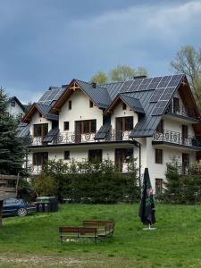 uma casa com um telhado com um banco e um guarda-chuva em Willa Dunajcówka em Szczawnica