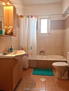 La salle de bains est pourvue d'une baignoire, d'un lavabo et de toilettes. dans l'établissement Zafeiris Apartments, à Livadia